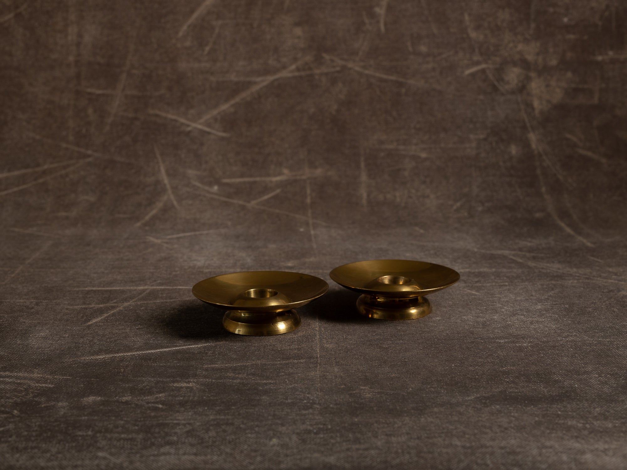 Paire de flambeaux soucoupe en laiton, Suède (vers 1965)..Pair of brass candle holders, Sweden (circa 1965)