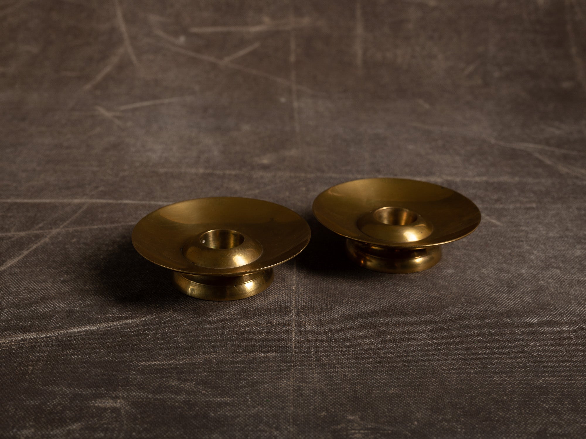 Paire de flambeaux soucoupe en laiton, Suède (vers 1965)..Pair of brass candle holders, Sweden (circa 1965)