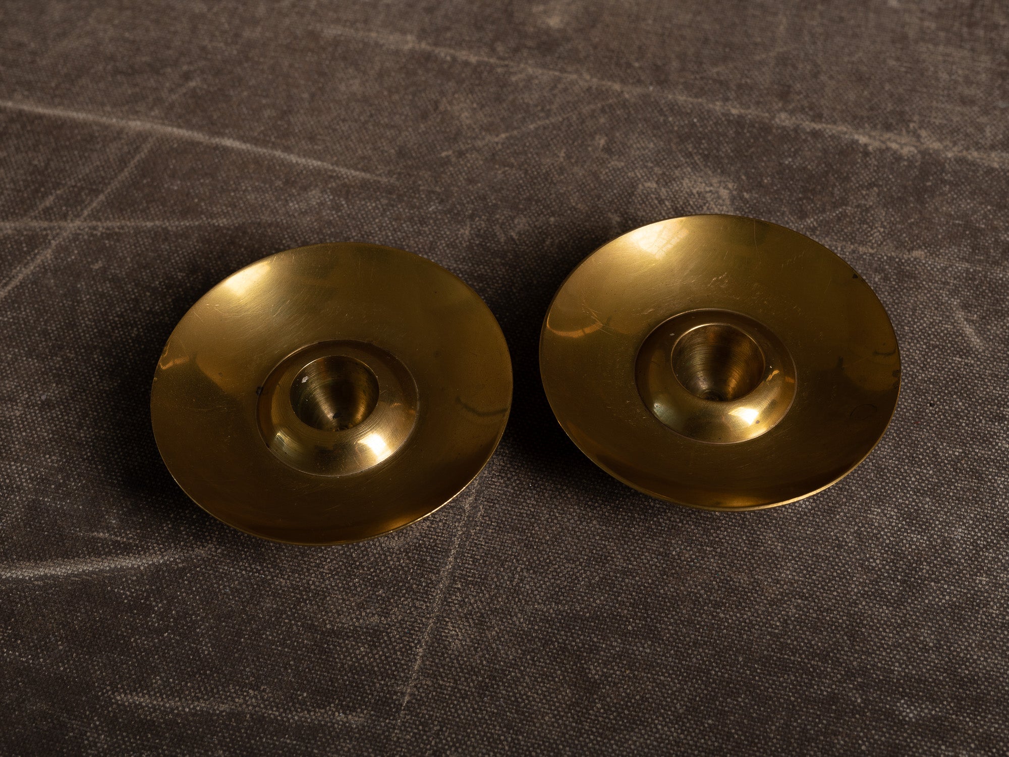 Paire de flambeaux soucoupe en laiton, Suède (vers 1965)..Pair of brass candle holders, Sweden (circa 1965)