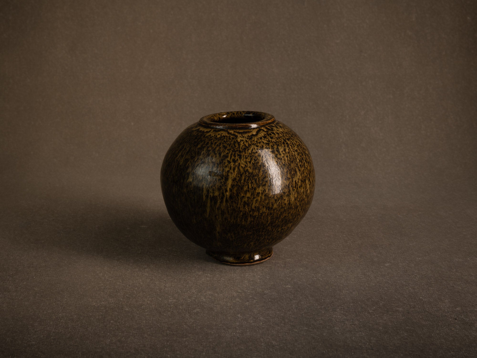 Vase boule en grès à émail goutte d'huile, France (circa 1980)..Stoneware sphere vase with oil-spot glaze, France (circa 1980)