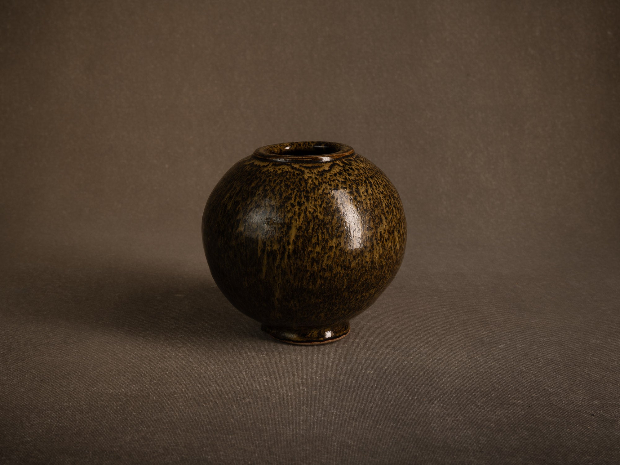 Vase boule en grès à émail goutte d'huile, France (circa 1980)..Stoneware sphere vase with oil-spot glaze, France (circa 1980)